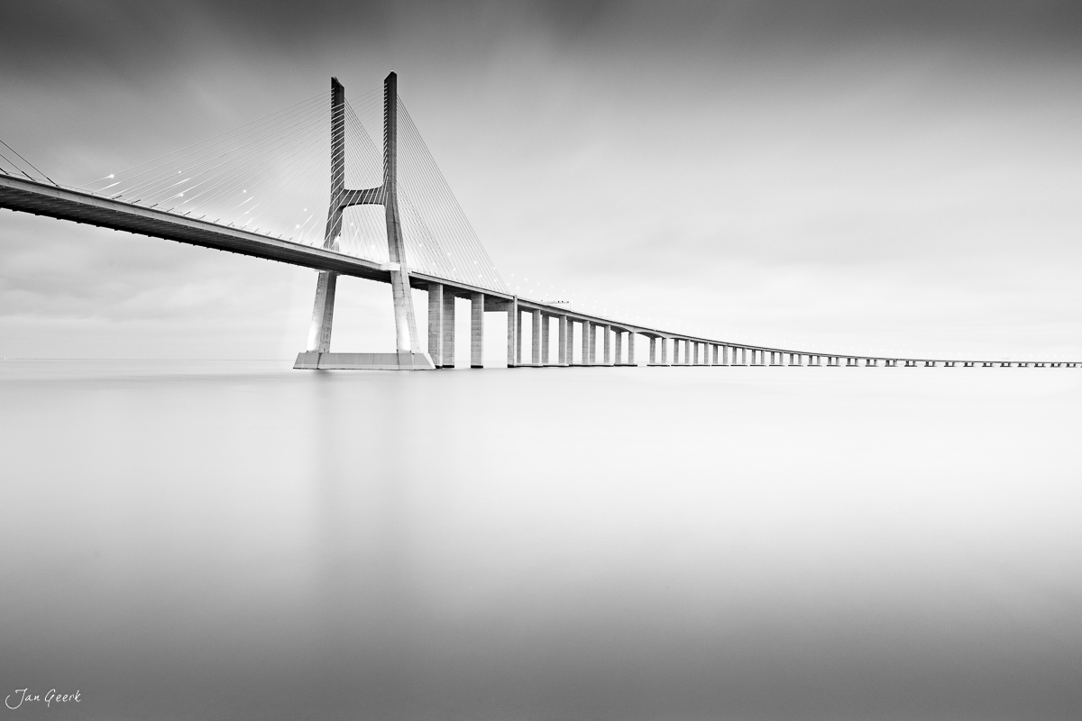 Moderne Hängebrücke über ruhiges Wasser in Lissabon, Schwarzweiss-Architekturaufnahme, Portugal – Jan Geerk Fotograf Basel