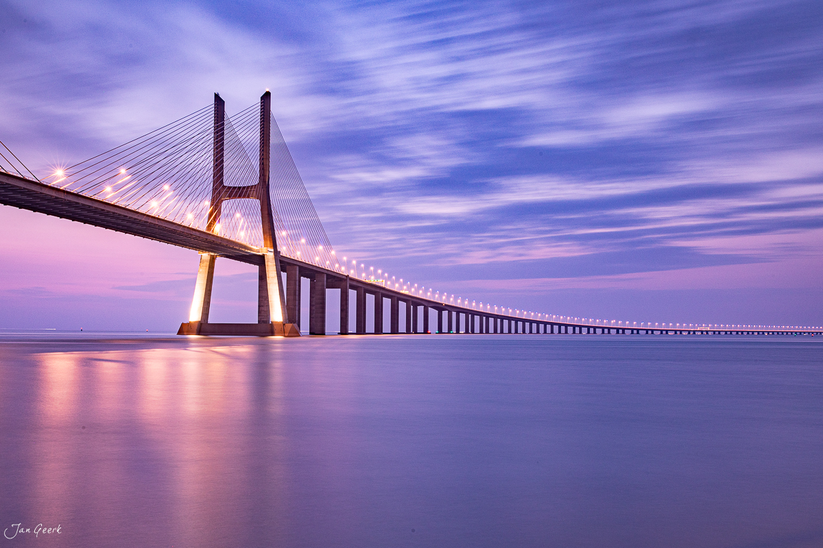 Beleuchtete Hängebrücke Vasco da Gama bei Sonnenuntergang über Wasser in Lissabon Portugal Schweiz Jan Geerk Fotograf Basel