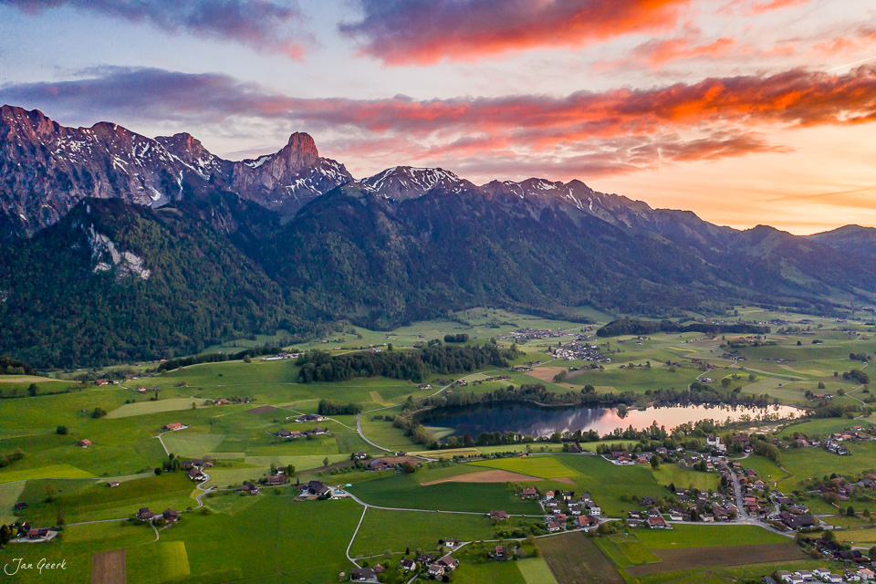 Luftaufnahme Amsoldingen mit Stockhornkette, Amsoldingersee und dramatischem Sonnenuntergang, Berner Oberland Schweiz – Jan Geerk Fotograf Basel