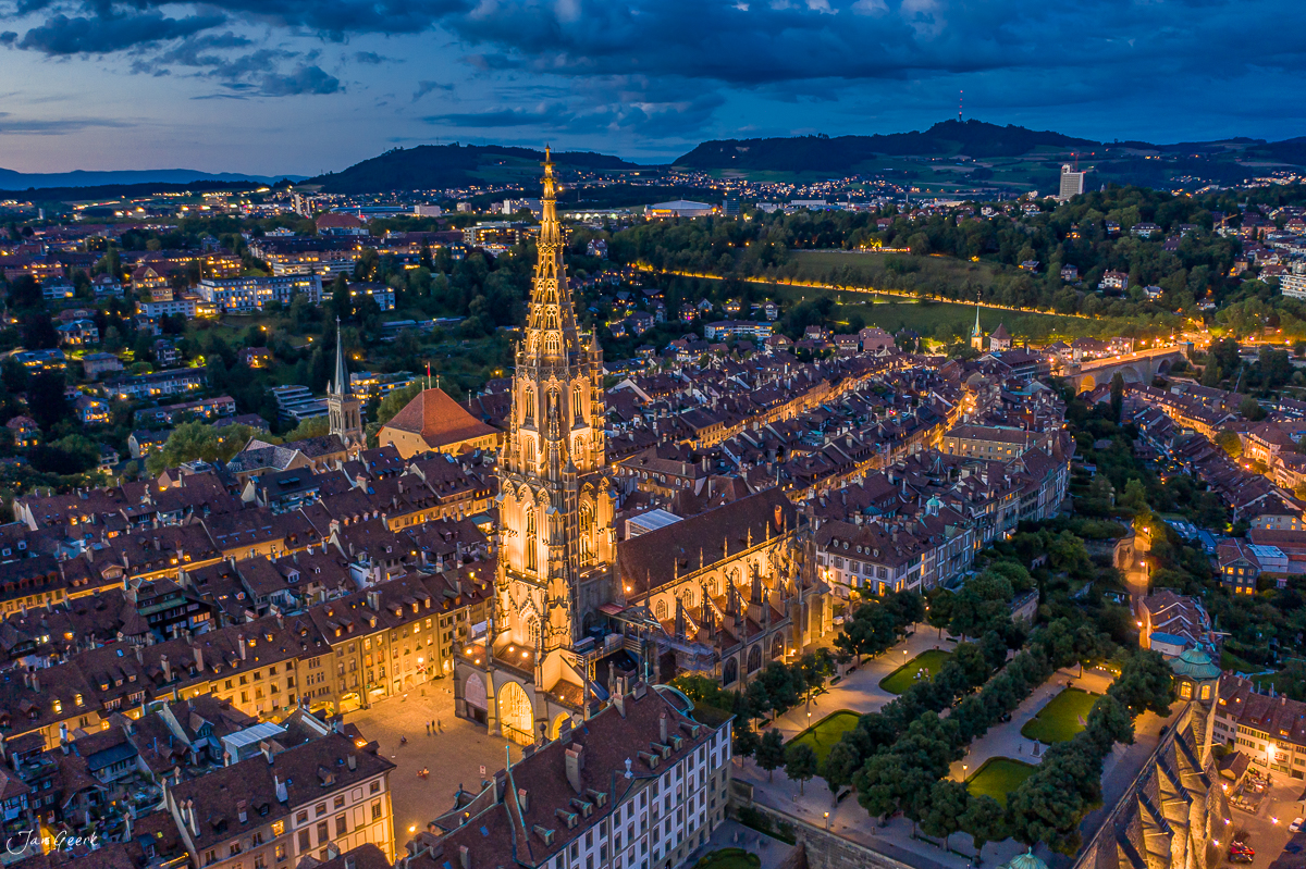 Berner Münster Luftaufnahme bei Dämmerung mit beleuchteter Altstadt und Aare-Schlaufe, Sommer, Bern Schweiz – Jan Geerk Fotograf Basel
