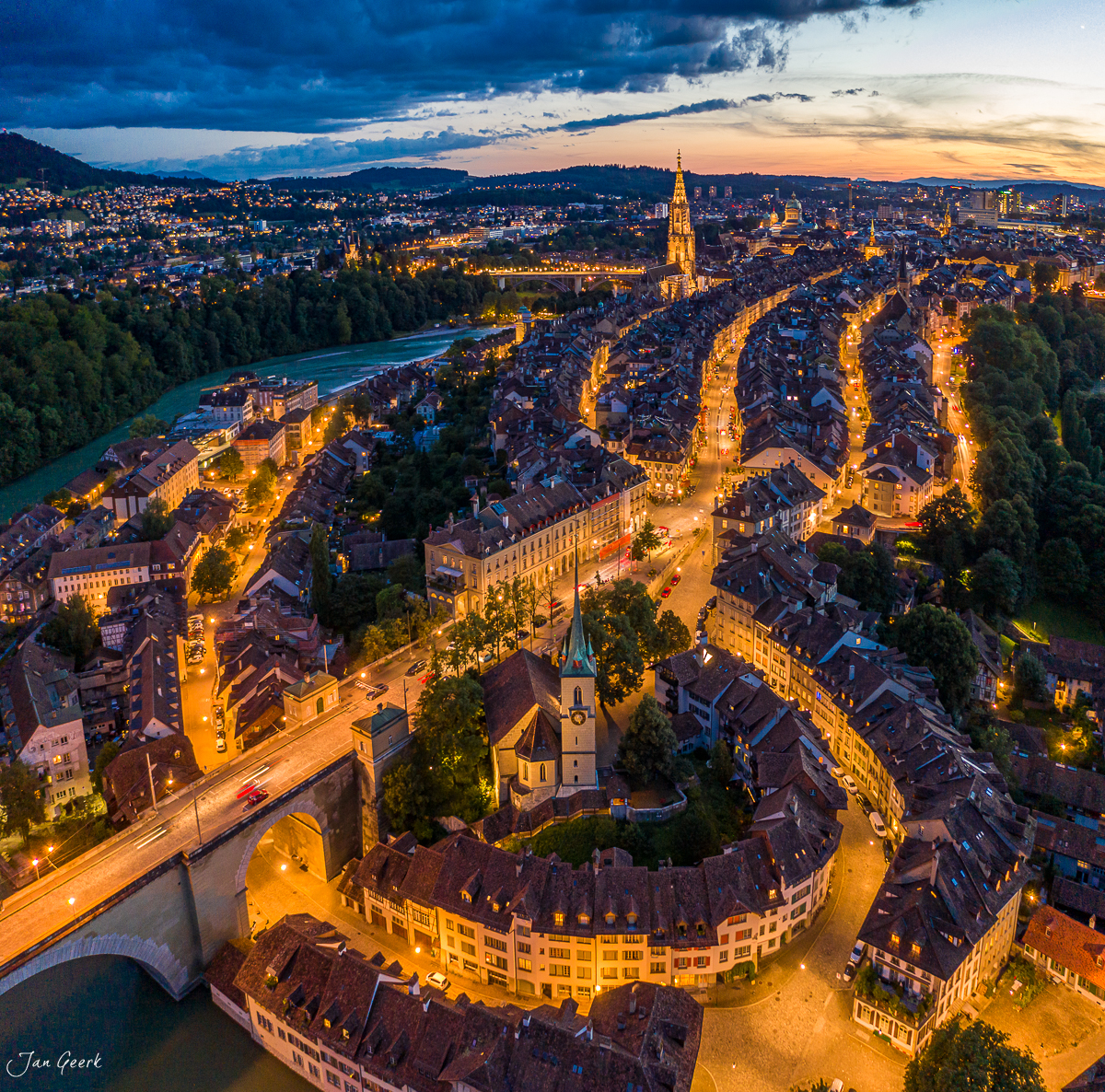 Luftaufnahme von Berns Altstadt mit Aare-Schleife, beleuchtete Gassen und Münster bei Sonnenuntergang, Berneroberland Schweiz – Jan Geerk Fotograf Basel