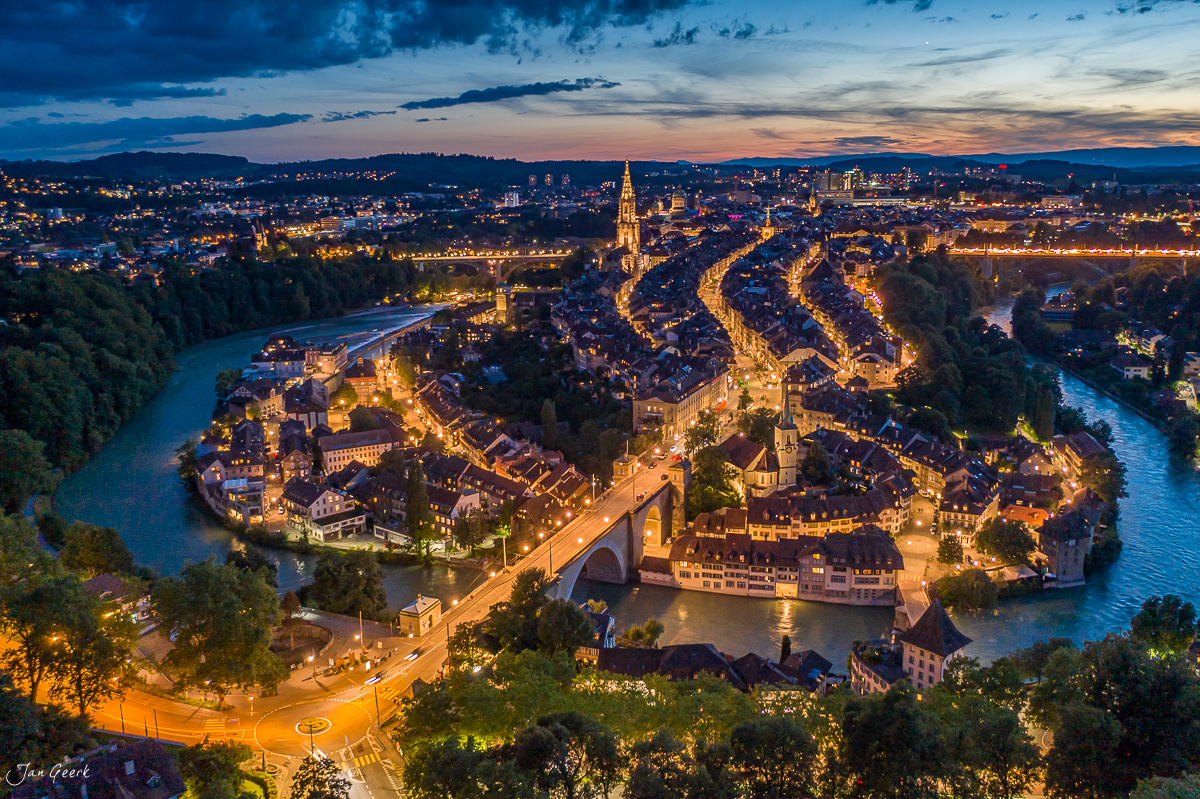 Luftaufnahme von Bern mit beleuchteter Altstadt, Aare-Schleife und Münster bei Dämmerung – Schweiz, Jan Geerk Fotograf Basel
