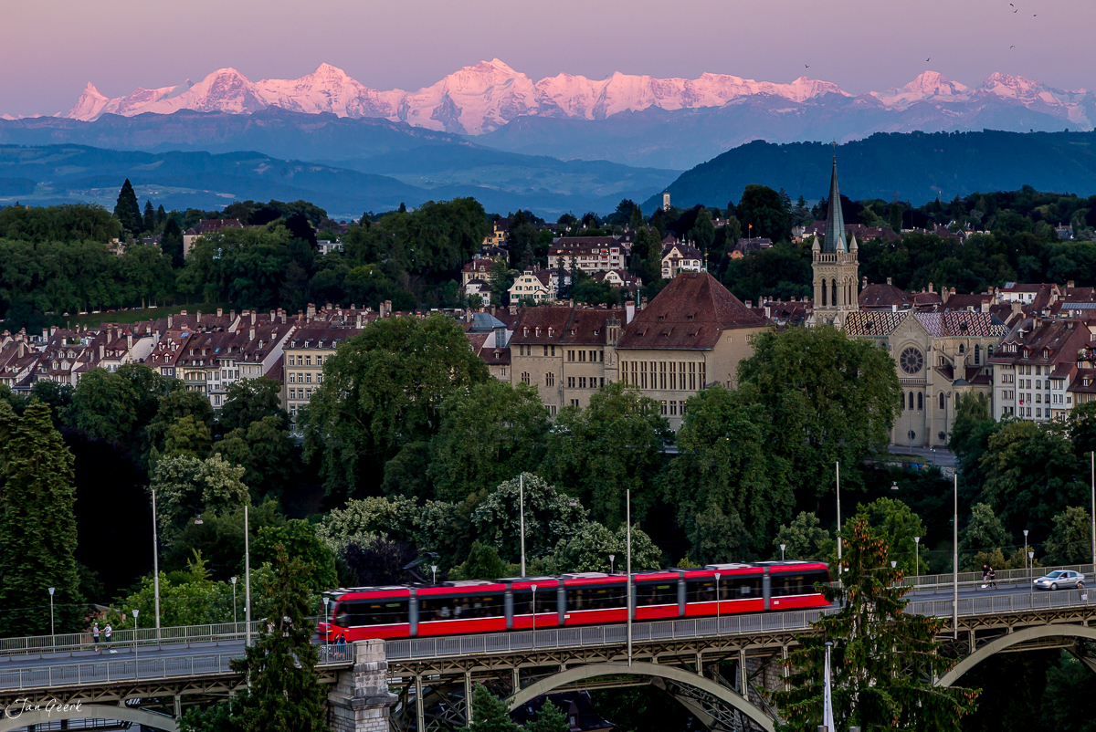 Rote Tram mit Alpenpanorama über Bern, Eiger Jungfrau Mönch im Hintergrund, Sommerlicht Schweiz – Jan Geerk Fotograf Basel