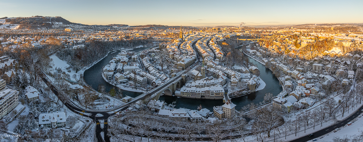 Panoramablick auf Bern mit schneebedeckter Altstadt, Aare-Schlaufe und Münster bei Sonnenaufgang im Winter – Jan Geerk Fotograf Basel