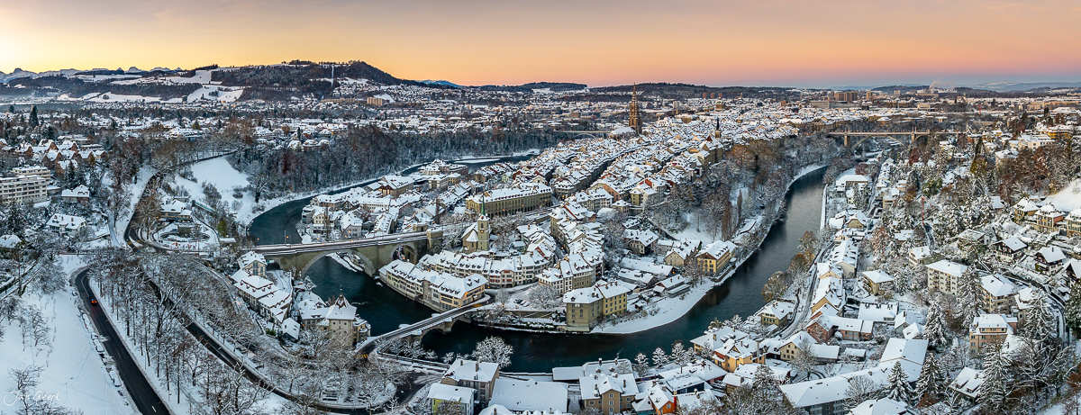 Winterliche Panorama-Luftaufnahme der Altstadt Bern mit verschneiten Dächern, Aare-Schlaufe und Münster bei Sonnenaufgang – Jan Geerk Fotograf Basel Schweiz