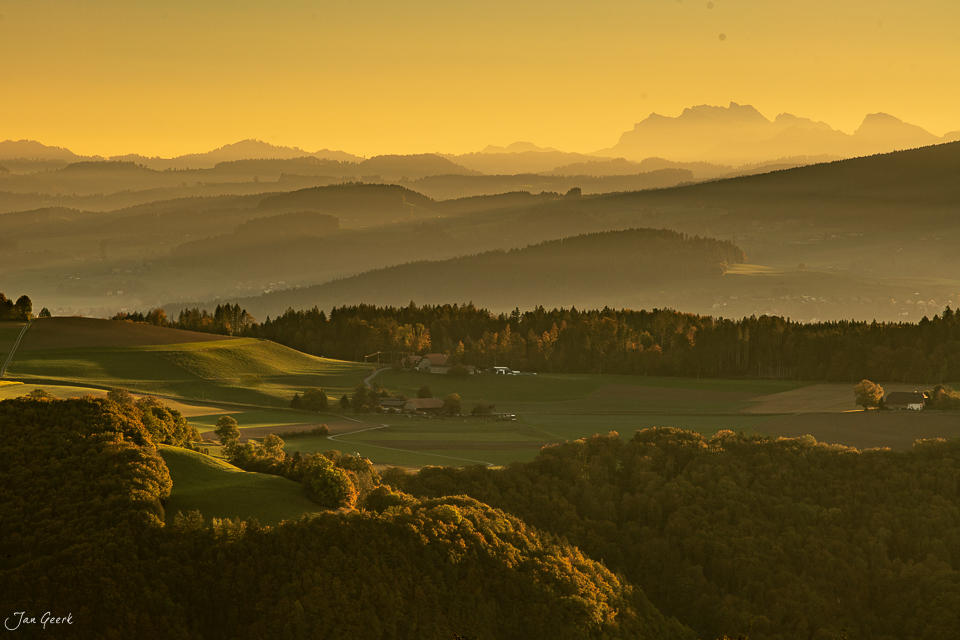 Herbstliche Berglandschaft bei Bütschelegg mit golden erleuchtetem Tal und fernen Alpen in der Schweiz – Fotograf Jan Geerk Basel
