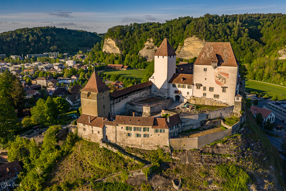 Luftaufnahme Schloss Burgdorf mit Türmen und Wehranlagen im Frühling, umgeben von grünen Wäldern und der Stadt Burgdorf im Hintergrund – Jan Geerk Fotograf Basel Schweiz