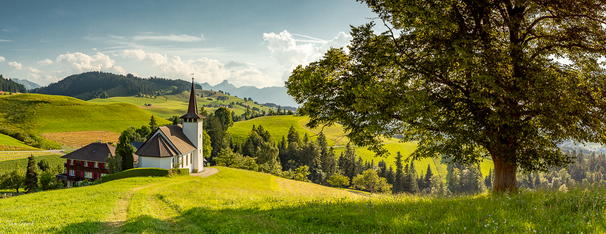 Kleine Kirche mit Glockenturm in grüner Hügellandschaft des Emmental, Sommerlicht, Berner Oberland Schweiz – Jan Geerk Fotograf Basel