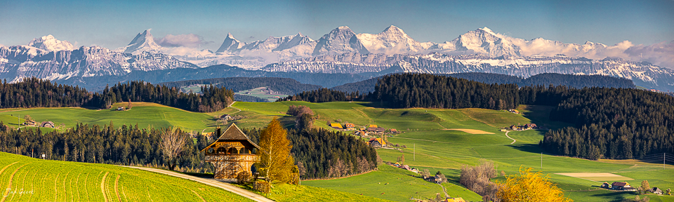 Frühlingspanorama mit Spycher-Bauernhof, Alpensicht und grünen Feldern im Emmental, Berner Oberland Schweiz – Jan Geerk Fotograf Basel
