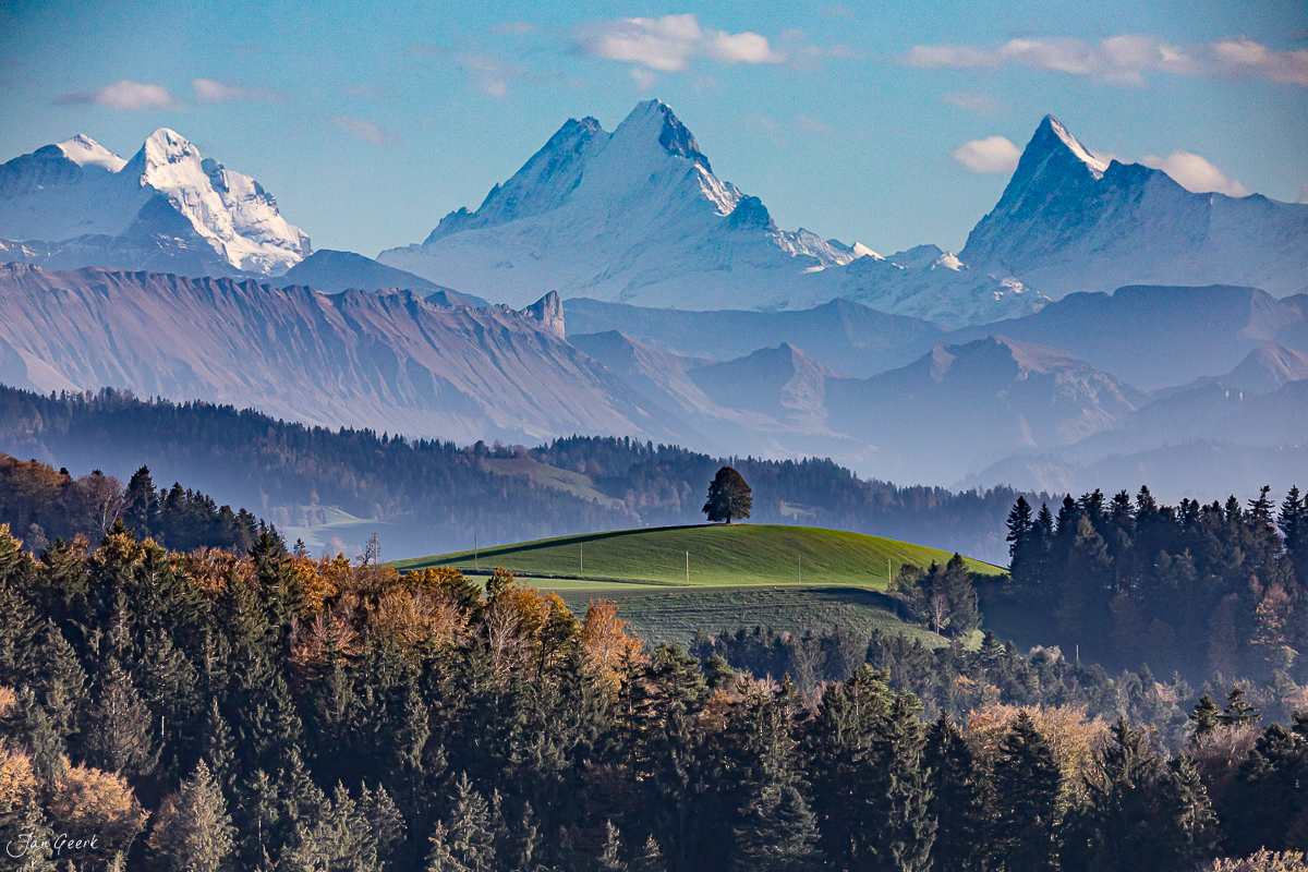 Herbstliche Hügellandschaft Emmental mit schneebedeckten Alpen und Wald in der Ferne Schweiz – Jan Geerk Fotograf Basel