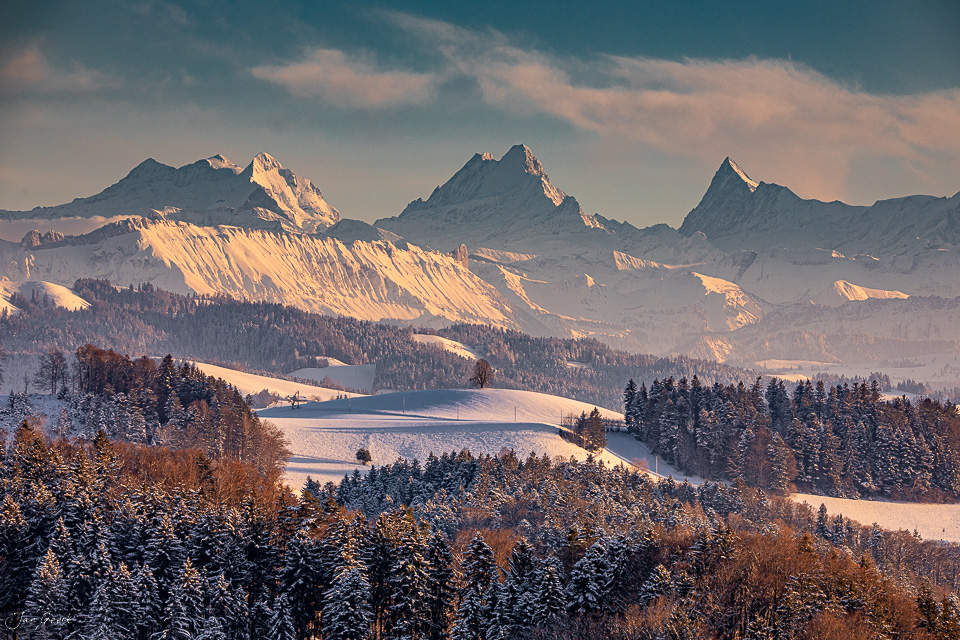 Schneebedeckte Berglandschaft mit Alpengipfeln bei Ferrenberg im Emmental, Wintersonne und Waldpanorama, Schweiz – Jan Geerk Fotograf Basel