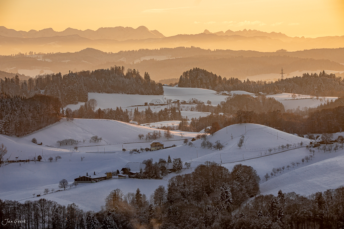 Schneebedeckte Hügellandschaft Emmental mit verschneiten Wäldern, Bergen und goldener Morgenstimmung in der Schweiz – Jan Geerk Fotograf Basel