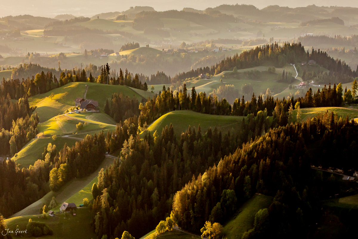 Luftaufnahme der Lüderenalp mit grünen Hügeln, Fichtenwäldern und verstreuten Bauernhöfen in Herbstlicht, Emmental Bern Schweiz – Jan Geerk Fotograf Basel