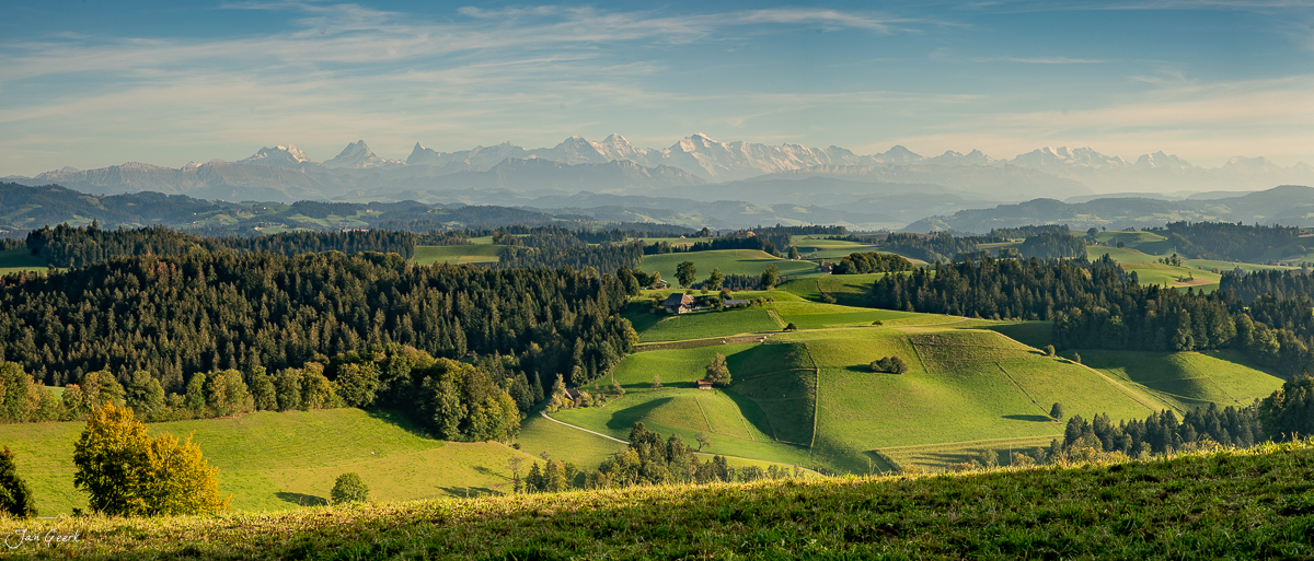 Alpensicht vom Emmental über grüne Hügel und Wälder mit Eiger, Jungfrau und Mönch am Horizont, Schweiz – Jan Geerk Fotograf Basel