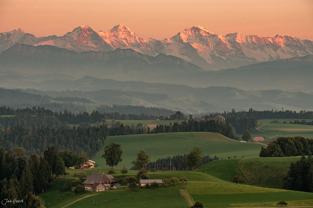 Alpenpanorama mit Eiger, Jungfrau und Mönch über dem Emmental, grüne Hügel, Bauernhöfe, Herbstlicht, Bern, Schweiz – Jan Geerk Fotograf Basel