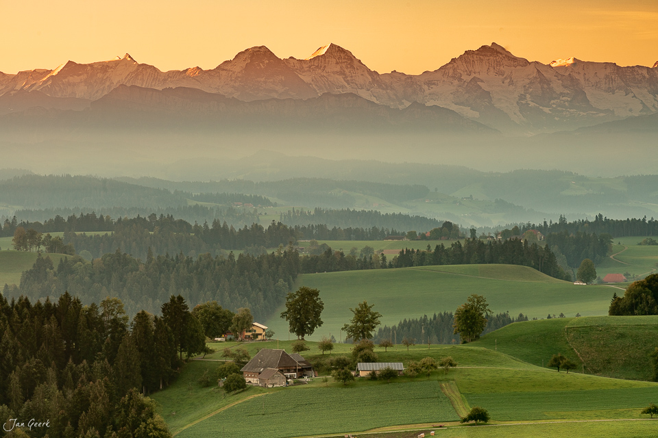 Emmental Lueg Landschaft mit Alpensicht, grüne Hügel und Bauernhäuser, golden illuminierte Berge, Schweiz – Jan Geerk Fotograf Basel