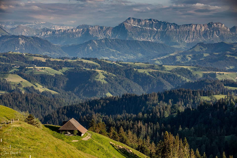 Alpenhütte auf grüner Wiese im Emmental mit Bergpanorama, Frühjahrslandschaft, Berner Oberland Schweiz – Jan Geerk Fotograf Basel
