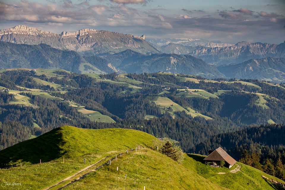 Grüne Hügellandschaft mit Alpenhütte und Bergpanorama im Emmental bei Sonnenlicht, Berner Oberland Schweiz – Jan Geerk Fotograf Basel