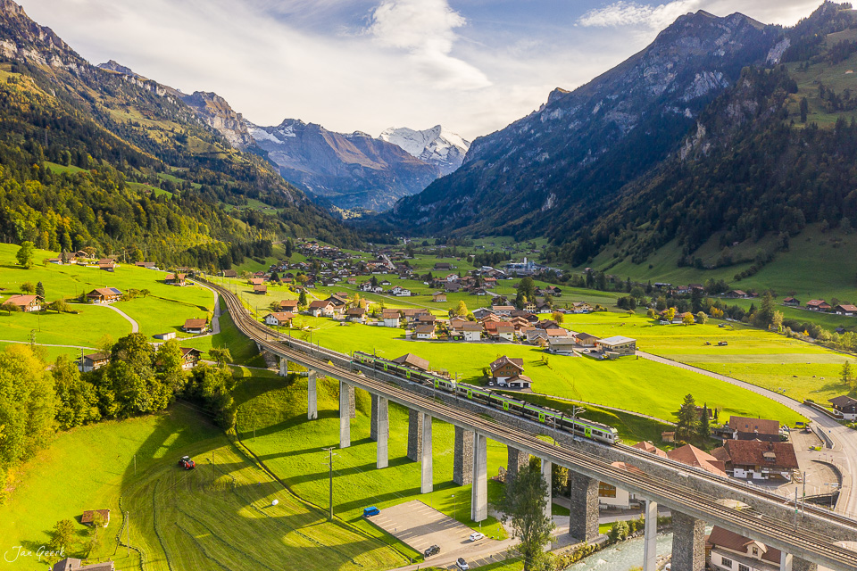 Alpental mit Dorf, Eisenbahnviadukt und schneebedeckten Bergen im Sommer, Frutigen Berner Oberland Schweiz – Jan Geerk Fotograf Basel