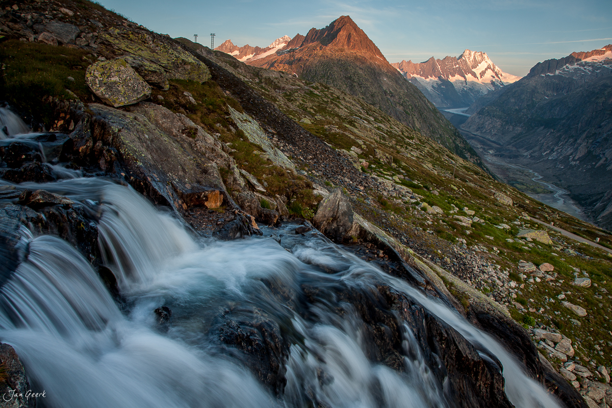 Wildbauer und Gebirgsbach am Grimselpass mit schneebedeckten Alpengipfeln in der Schweiz – Jan Geerk Fotograf Basel