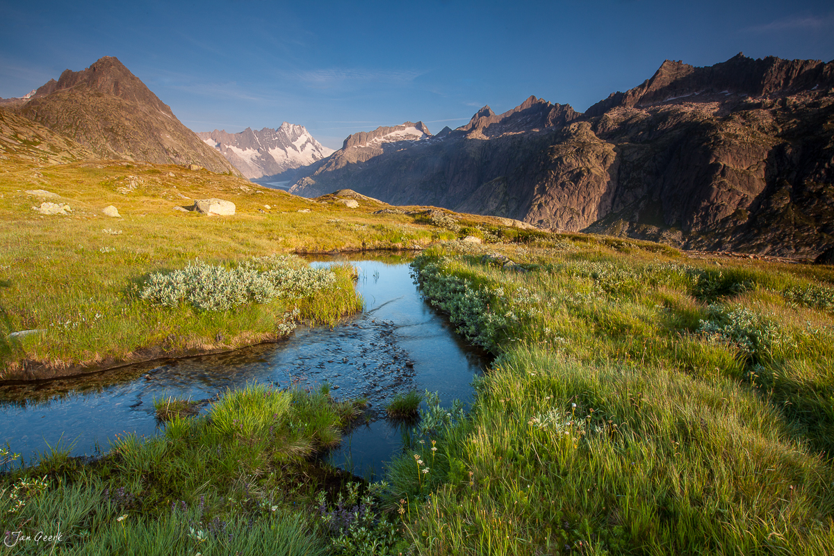 Bergbach und Berglandschaft mit schneebedeckten Gipfeln am Grimselpass in den Berner Alpen, Schweiz – Jan Geerk Fotograf Basel
