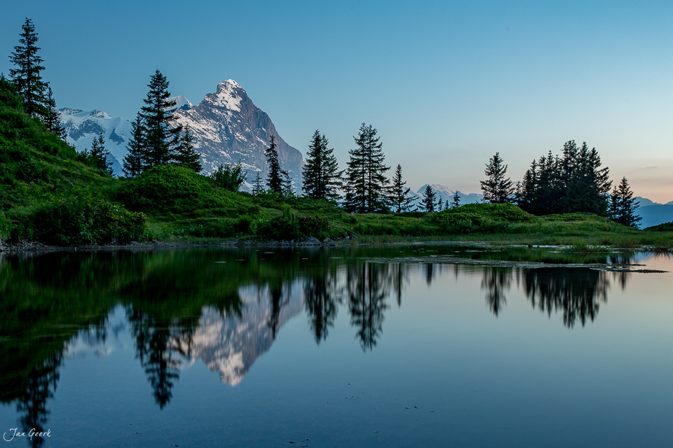 Alpensee mit Spiegelung von Bergwald und schneebedecktem Eiger bei Grosse Scheidegg, Sommer, Berner Oberland Schweiz – Jan Geerk Fotograf Basel