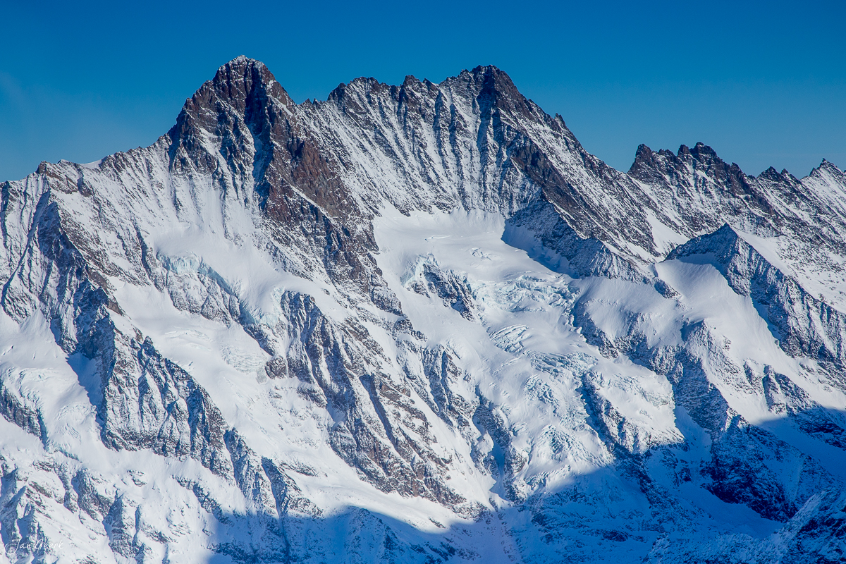 Schneebedeckte Bergkette in den Alpen Berner Oberland im Winter unter blauem Himmel, fotografiert aus dem Helikopter von Jan Geerk Fotograf Basel Schweiz