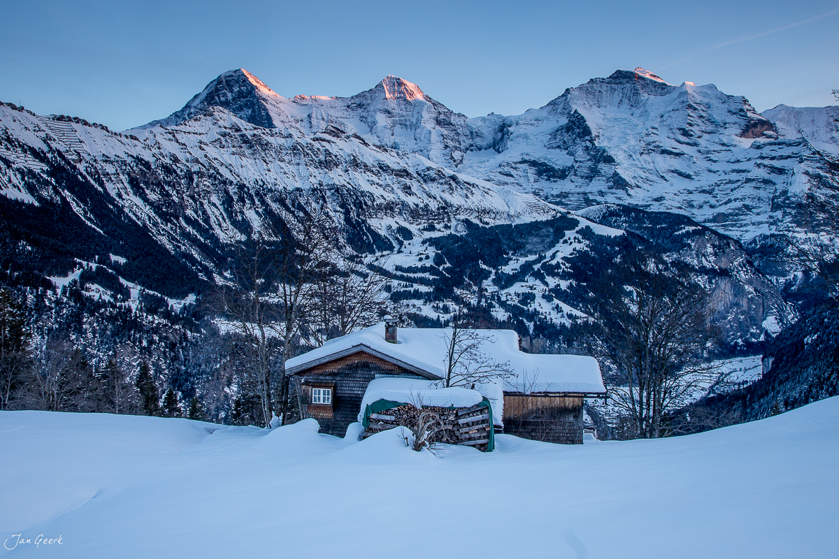 Schneebedeckte Berghütte im Berner Oberland mit verschneiten Alpen im Hintergrund, Winterstimmung in der Schweiz – Jan Geerk Fotograf Basel