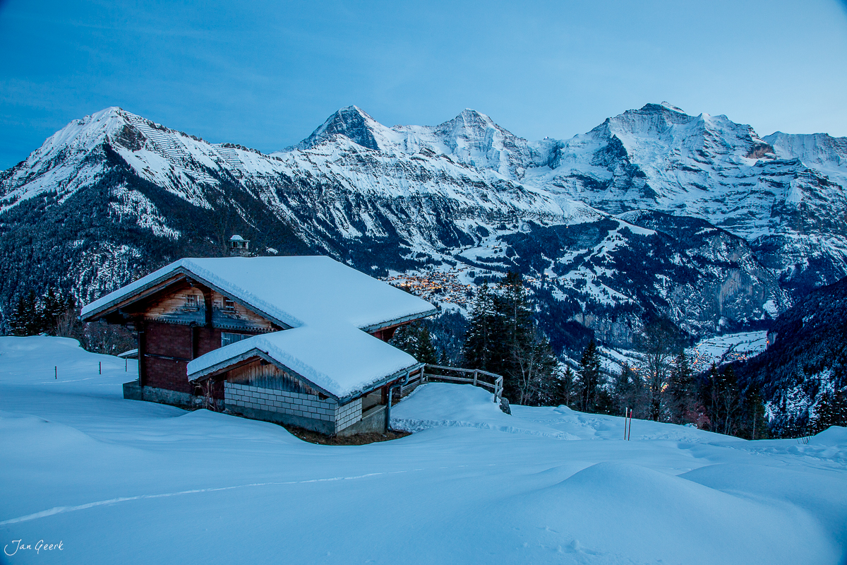 Traditionelle Alphütte im verschneiten Berner Oberland mit schneebedeckten Alpen im Hintergrund, Winterstimmung – Jan Geerk Fotograf Basel