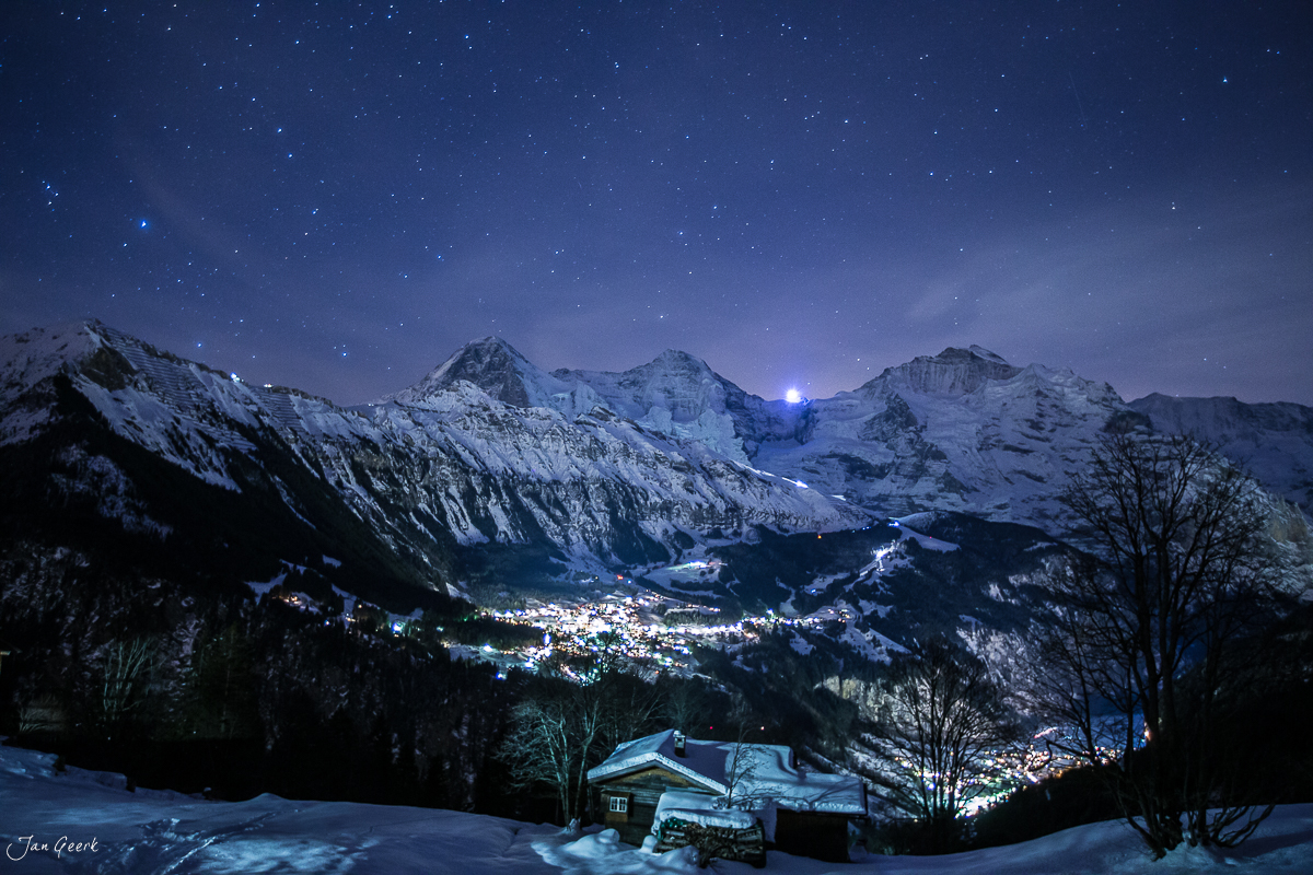 Nächtliches Bergpanorama mit verschneiten Alpengipfeln über beleuchteter Ortschaft im Berner Oberland Schweiz – Jan Geerk Fotograf Basel