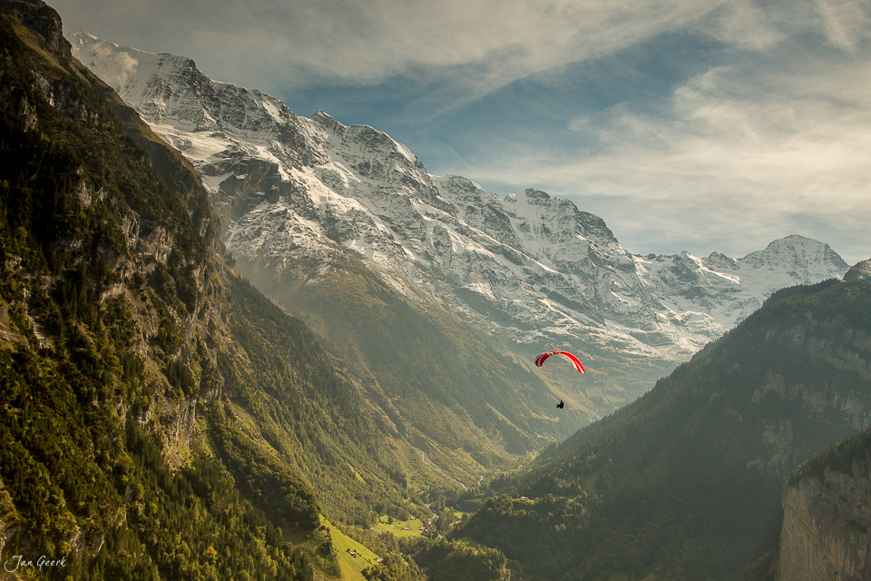 Gleitschirm über dem Lauterbrunnen-Tal mit schneebedeckten Alpen, grüne Berghänge, Sommerlicht, Berner Oberland Schweiz – Jan Geerk Fotograf Basel