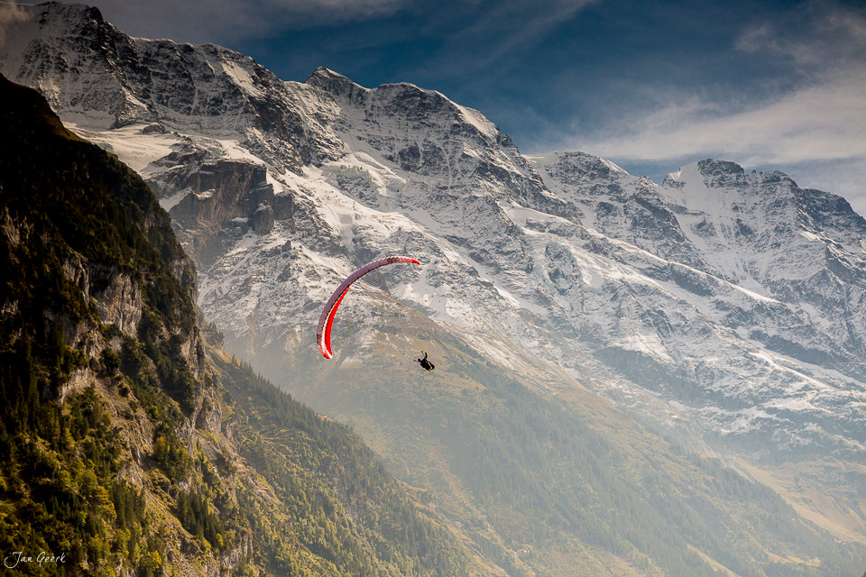 Gleitschirmflieger über Lauterbrunnen mit verschneiten Alpen im Hintergrund, Berner Oberland Schweiz – Jan Geerk Fotograf Basel