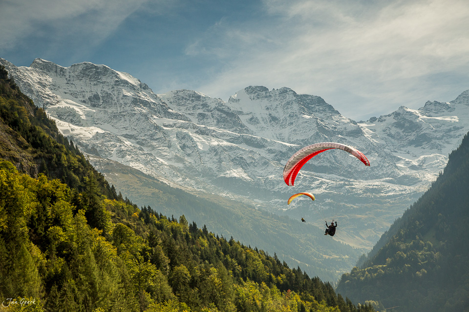Gleitschirmflieger über Lauterbrunnen mit schneebedeckten Alpen, Jungfrau und grünen Wäldern im Berner Oberland Schweiz – Jan Geerk Fotograf Basel