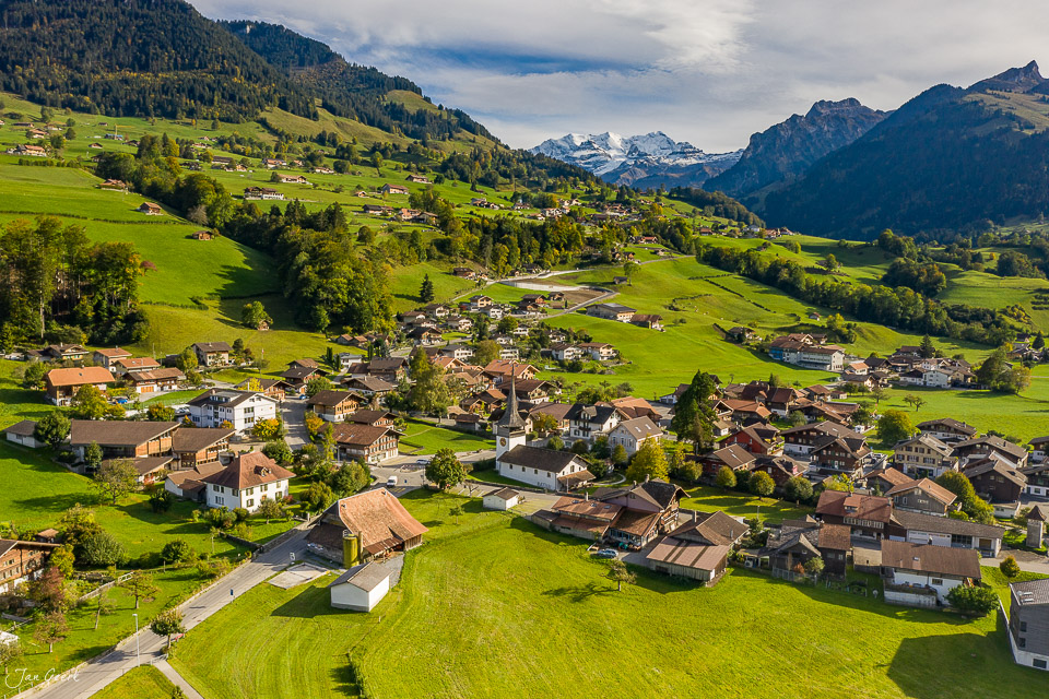 Luftaufnahme des Dorfes Reichenbach im Kandertal mit grünen Wiesen, Berghängen und Alpenpanorama im Sommer, Berner Oberland Schweiz – Jan Geerk Fotograf Basel