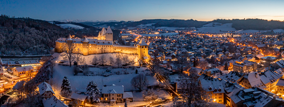 Schloss Burgdorf verschneit in der Winterdämmerung, beleuchtete Altstadt und umliegende Dörfer im Emmental, Schweiz – Jan Geerk Fotograf Basel