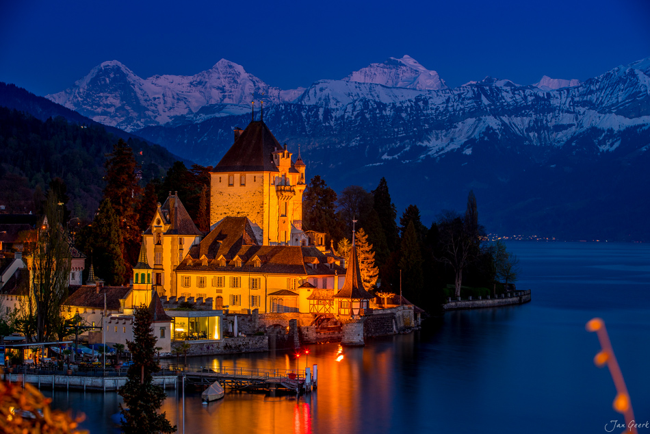 Schloss Oberhofen illuminiert am Thunersee mit verschneiten Alpen im Frühling, Berner Oberland Schweiz – Jan Geerk Fotograf Basel