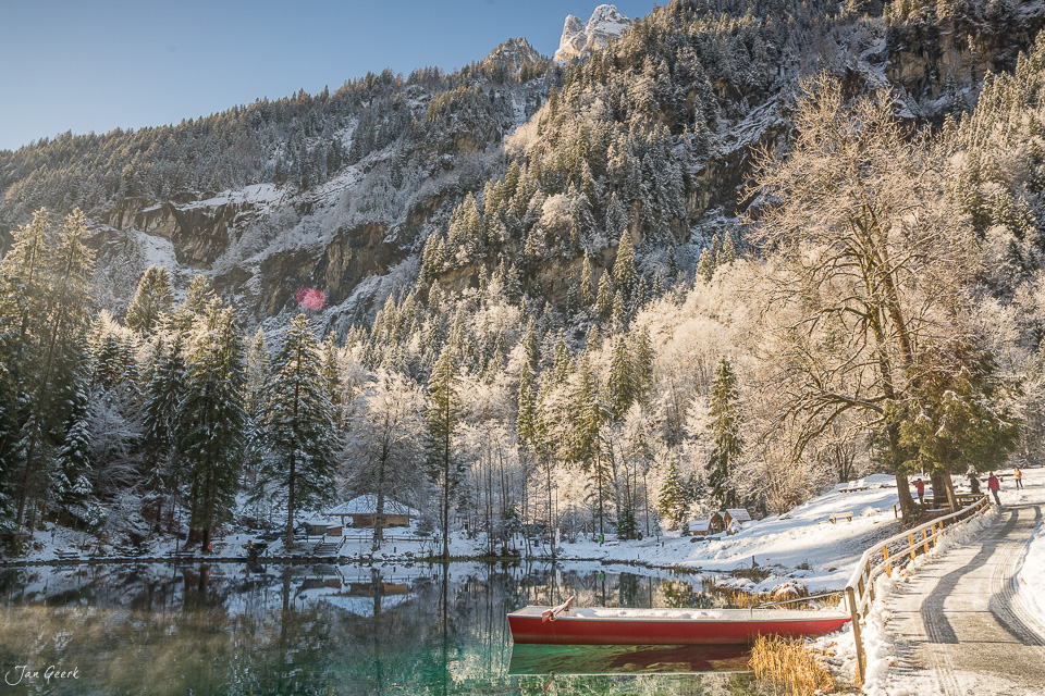 Rootes Boot am Blausee mit verschneiten Bergen und Wald im Winterlicht, Kandersteg Berner Oberland Schweiz – Jan Geerk Fotograf Basel