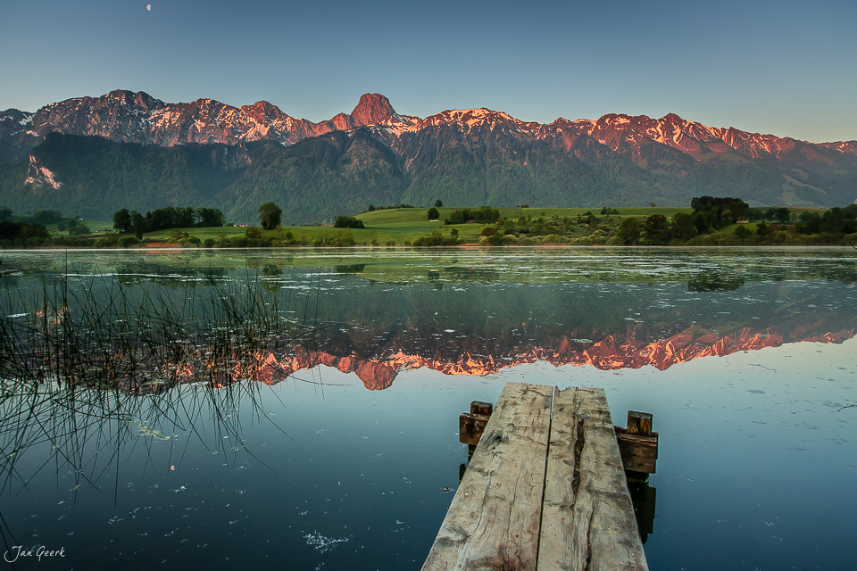 Holzsteg am Üebeschisee mit Spiegelung der Stockhornkette im Wasser, Sonnenaufgang Frühling Berner Oberland Schweiz Jan Geerk Fotograf Basel