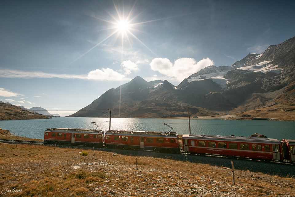 Rhätische Bahn am Lago Bianco mit schneebedeckten Bergen im Herbst, Berninapass Graubünden Schweiz – Jan Geerk Fotograf Basel