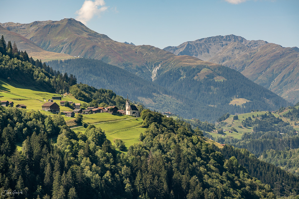 Alpendorf Cavardiras mit Kirche, grüne Wiesen und Bergwald im Sommer in der Surselva Graubünden Schweiz – Jan Geerk Fotograf Basel