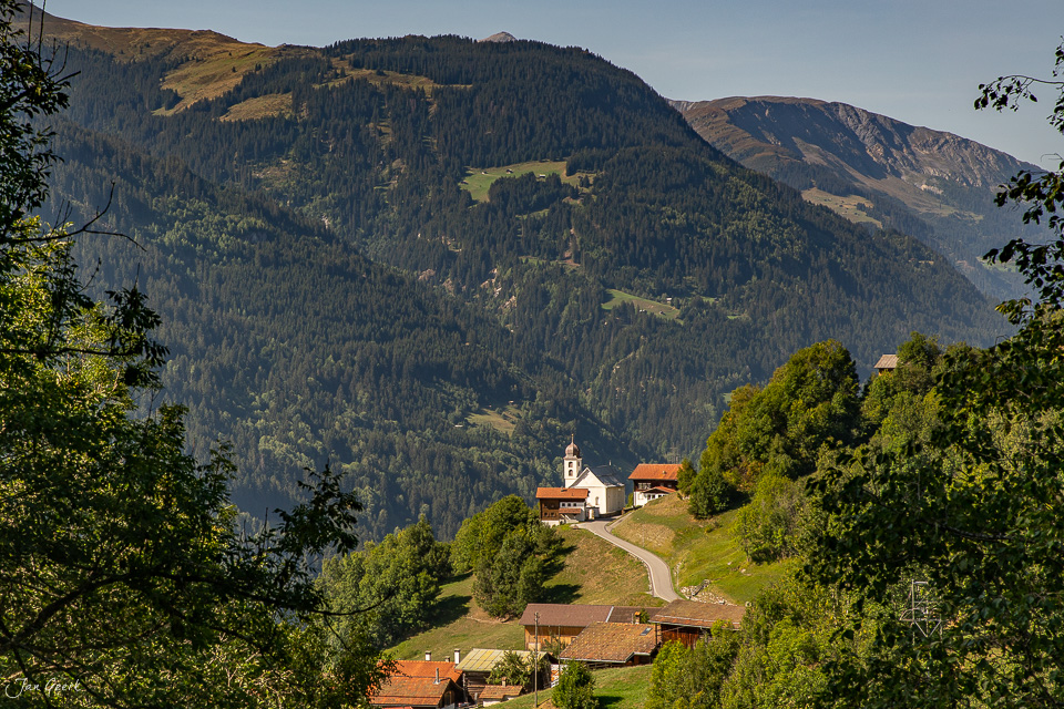 Dorf Dardin mit Kirche in alpiner Berglandschaft im Sommer, Surselva Graubünden Schweiz – Jan Geerk Fotograf Basel