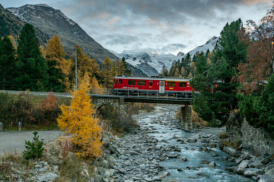 Roter Bernina Express Zug auf Brücke über Fluss, goldene Lärchen Herbst Engadin Graubünden Schweiz – Jan Geerk Fotograf Basel