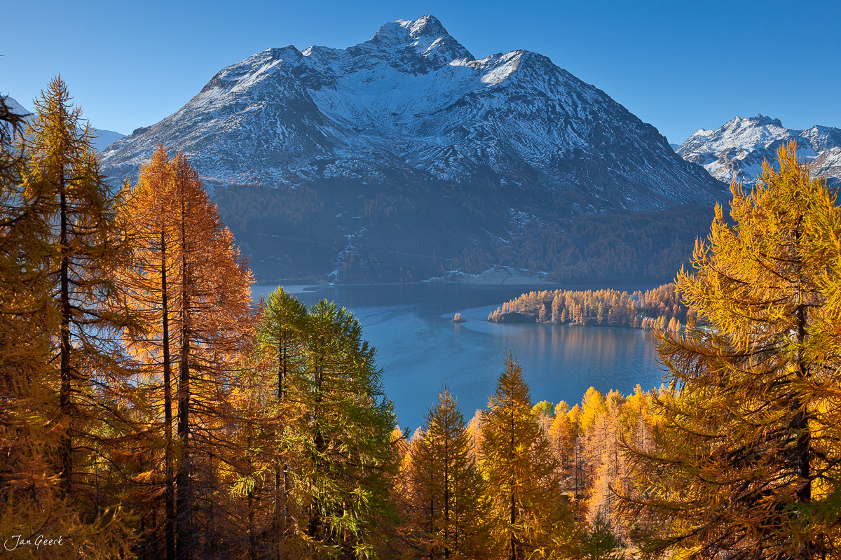 Bergsee mit verschneitem Gipfel Herbstlaerchen Engadin Graubuenden Schweiz Jan Geerk Fotograf Basel