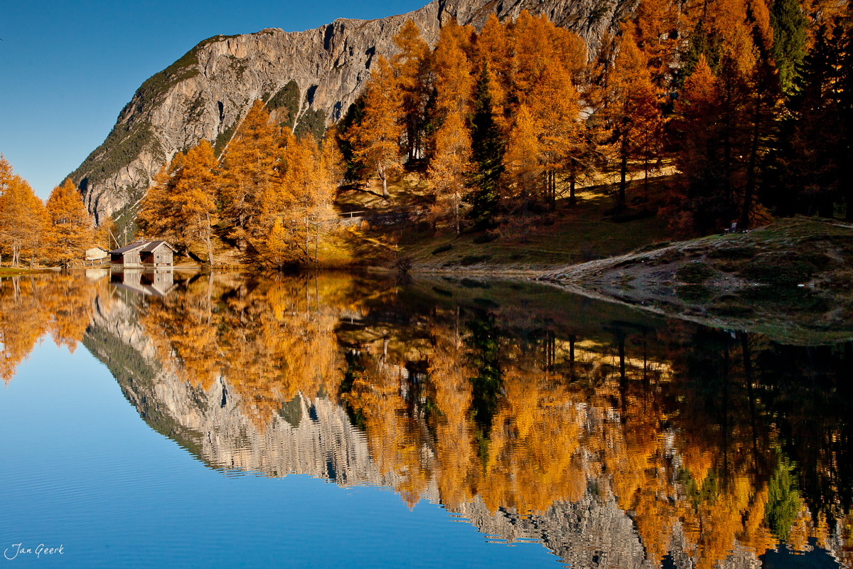 Spiegelglatter Bergsee mit goldenen Lärchen und Kalkfelsen Herbst Engadin Graubünden Schweiz – Jan Geerk Fotograf Basel