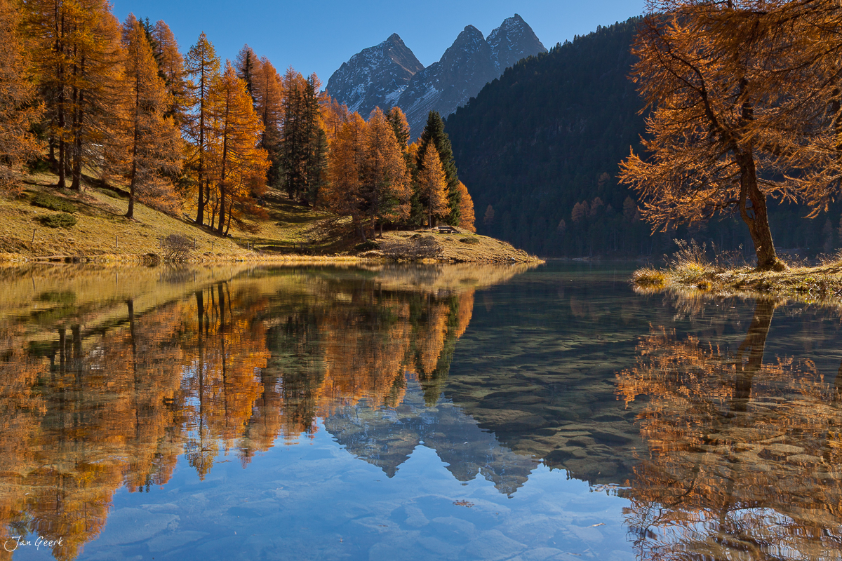 Herbstlicher Bergsee mit goldenen Lärchen Spiegelung Engadin Graubünden Schweiz Jan Geerk