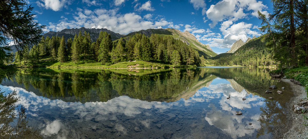 Spiegelglatter Bergsee mit Lärchenwäldern und Bergpanorama im Engadin, Graubünden, Schweiz – Jan Geerk Fotograf Basel