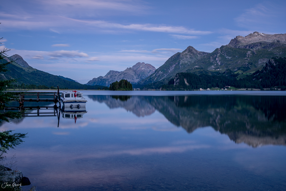 Segelboot und Berggipfel spiegeln sich im glasklaren Wasser des Silsersees im Engadin, Graubünden, Schweiz – Jan Geerk Fotograf Basel