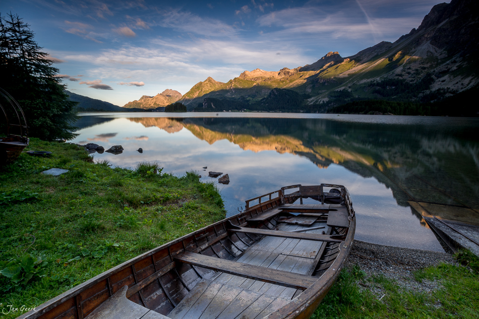 Holzboot am Seeufer des Silsersee mit schneebedeckten Bergen in goldener Abendstimmung, Engadin Graubünden Schweiz – Jan Geerk Fotograf Basel