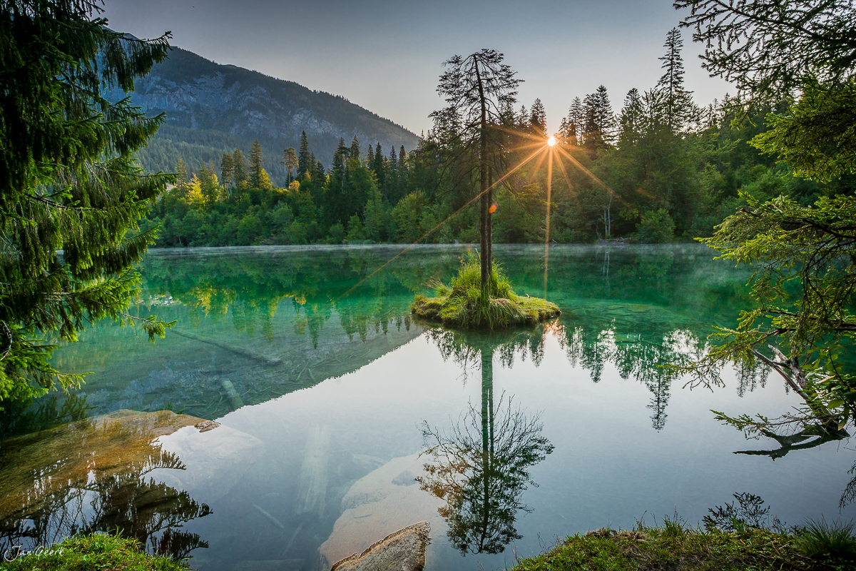 Spiegelnder Bergsee mit Fichten und Sonnenlicht, Crestasee Flims Sommer Graubünden Schweiz – Jan Geerk Fotograf Basel