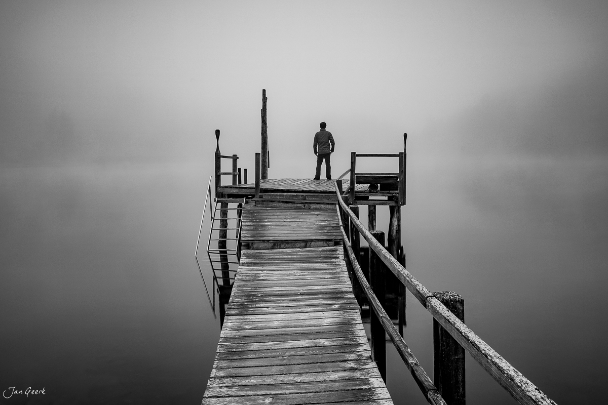 Mann auf Holzsteg am Stazersee in Graubünden, Nebel und Berg-Atmosphäre, Engadin Schweiz – Jan Geerk Fotograf Basel